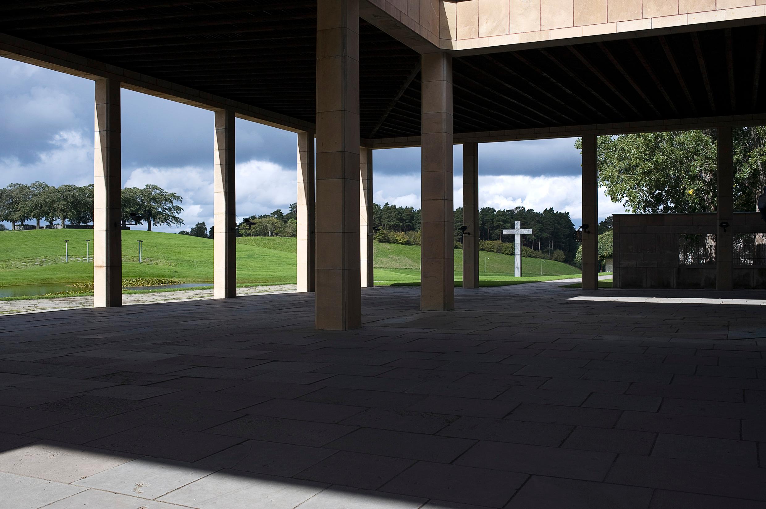 A view onto the grassy areas of the Woodland Cemetary, through the pillars of a chapel.