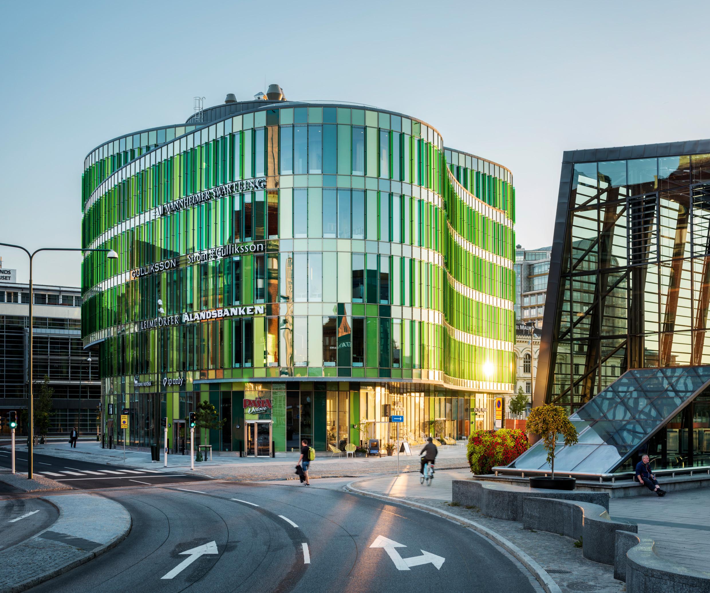 A green glass building in a city setting.