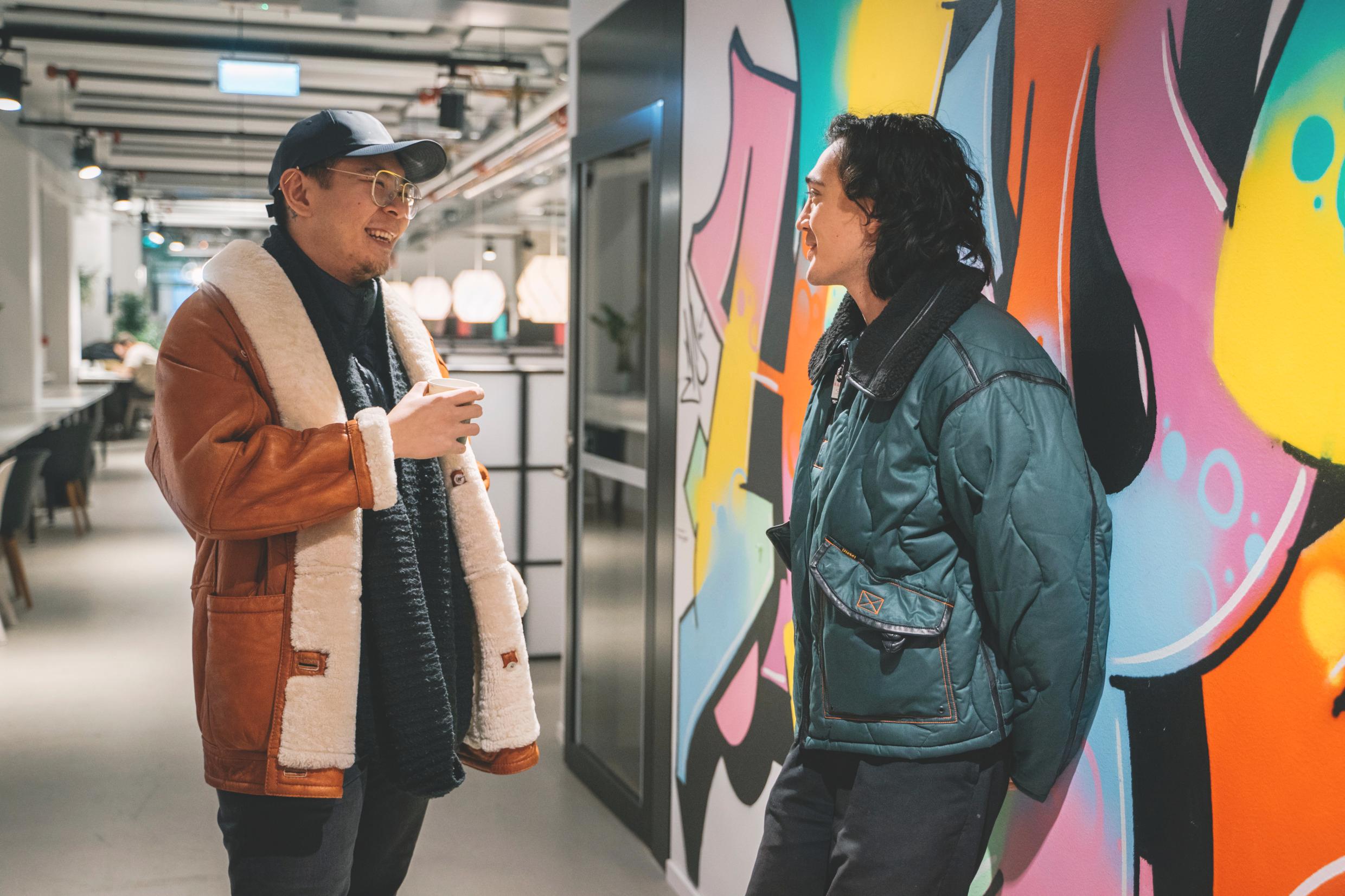 Two people talking together in a shared workspace.