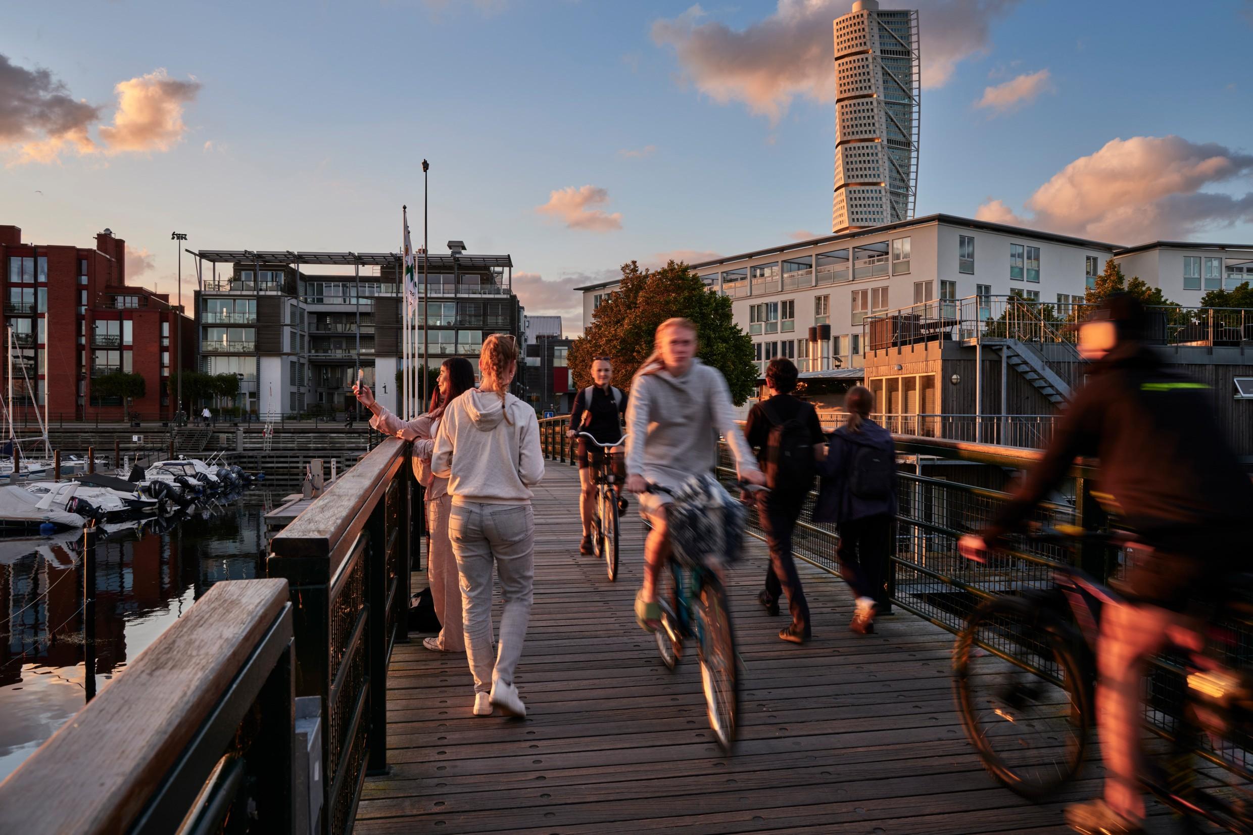 People riding bikes on a bridge in a Swedish town
