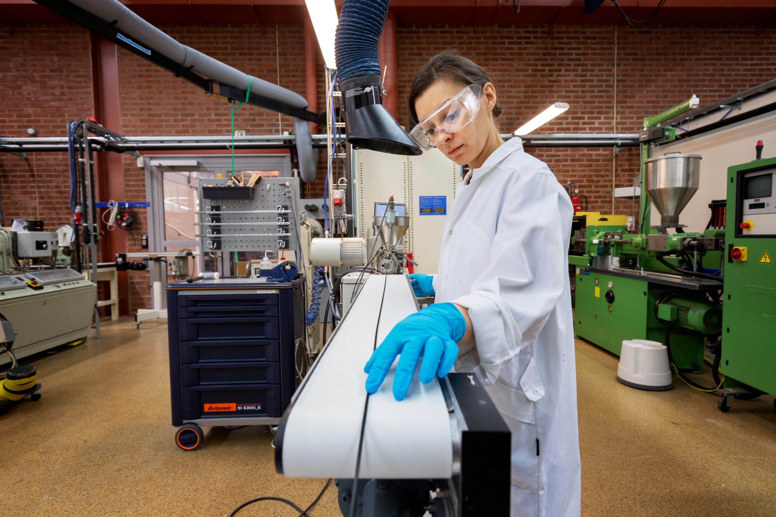 A woman in a lab coat and goggles stands by a machine. A glimpse of innovation in Sweden.
