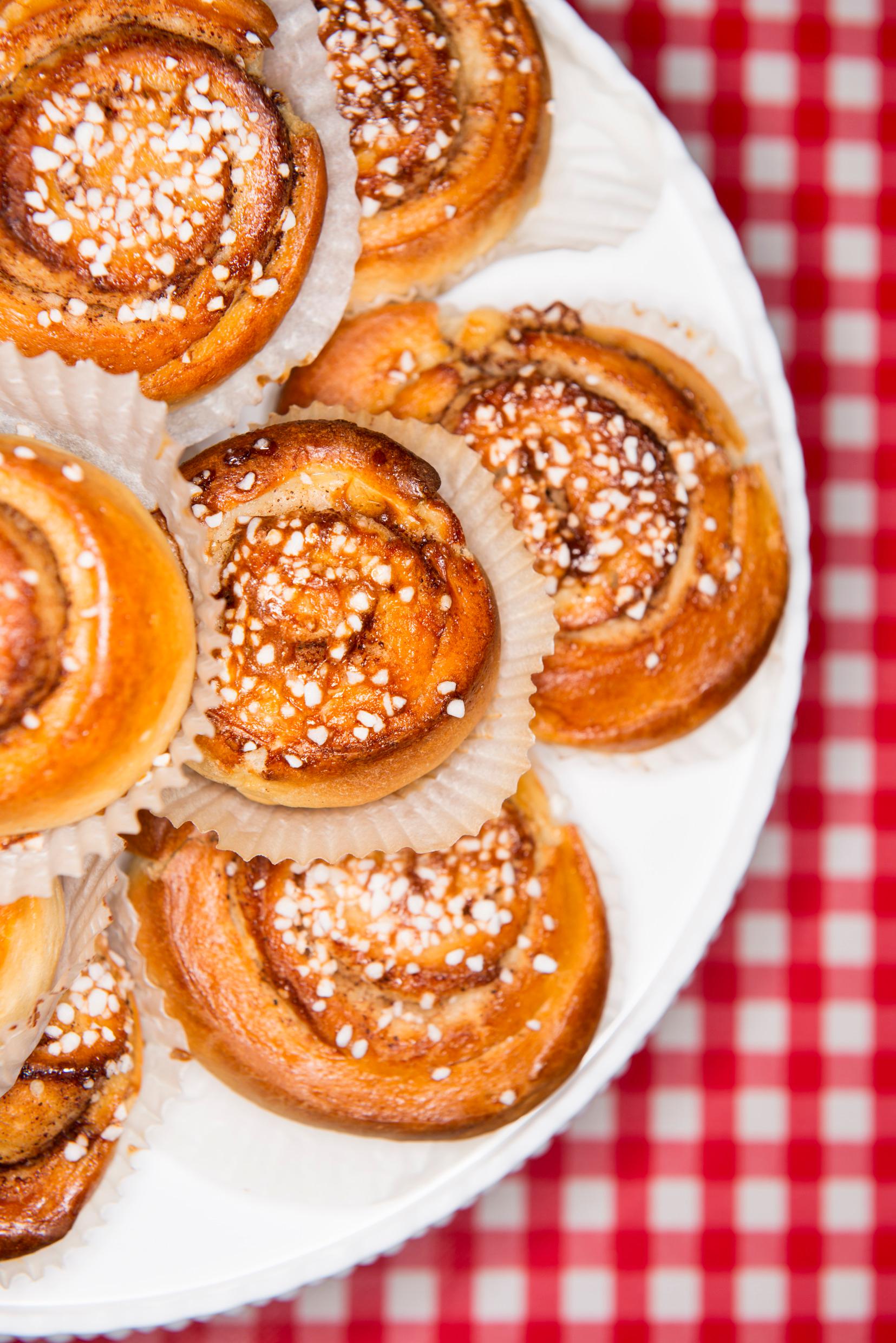 Seen from above, a plate filled with cinnamon buns on top of a red and white table cloth.