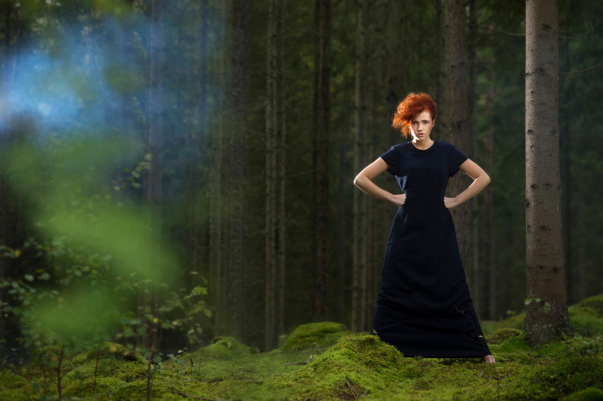 A woman in a dress standing in a forest. The dress is made of paper – an example of Swedish recycling innovation.