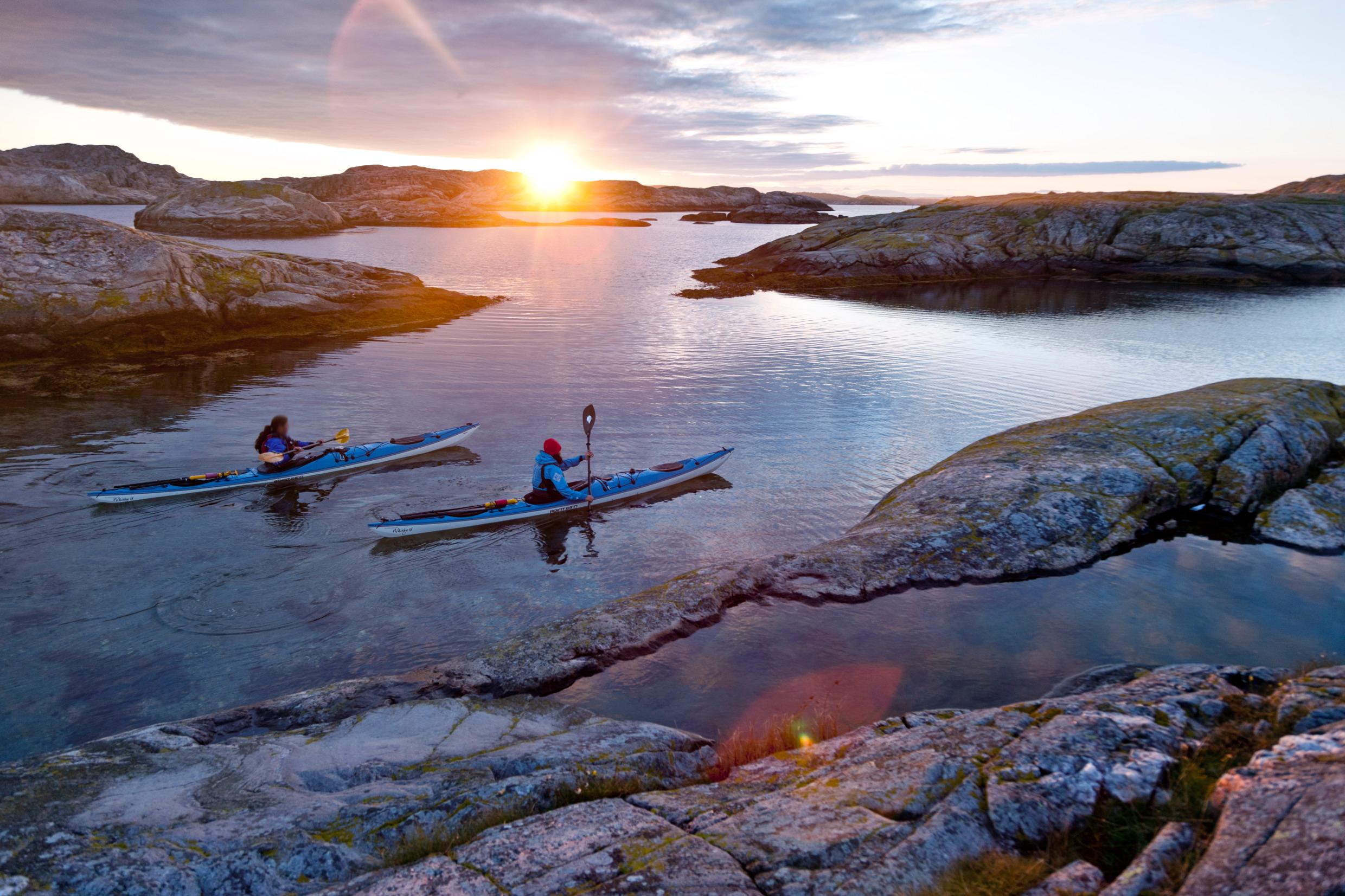 Two kayaks make their way past islands of the Bohuslän coast as the sun sets.