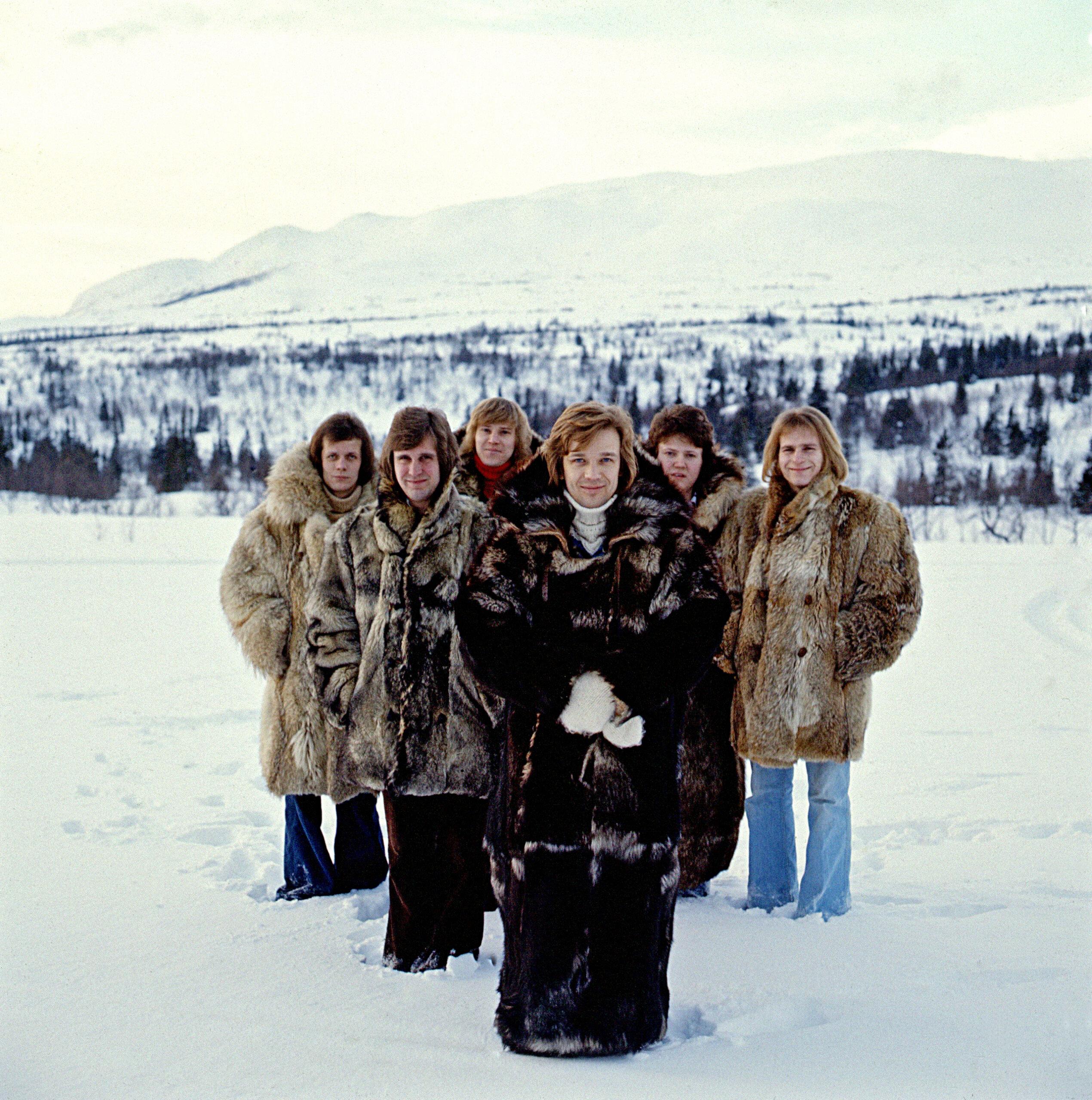 The five men of Blue Swede all wearing furs and standing in a snowy white landscape, Björn Skifs at the front.