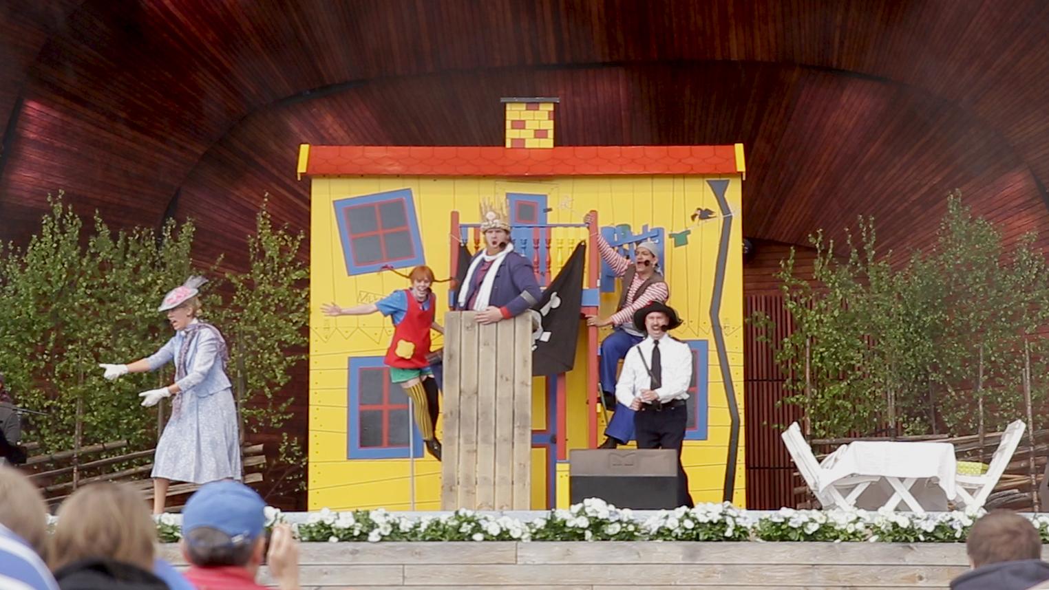 A shot from a Pippi Longstocking play live on stage. Five actors can be seen.
