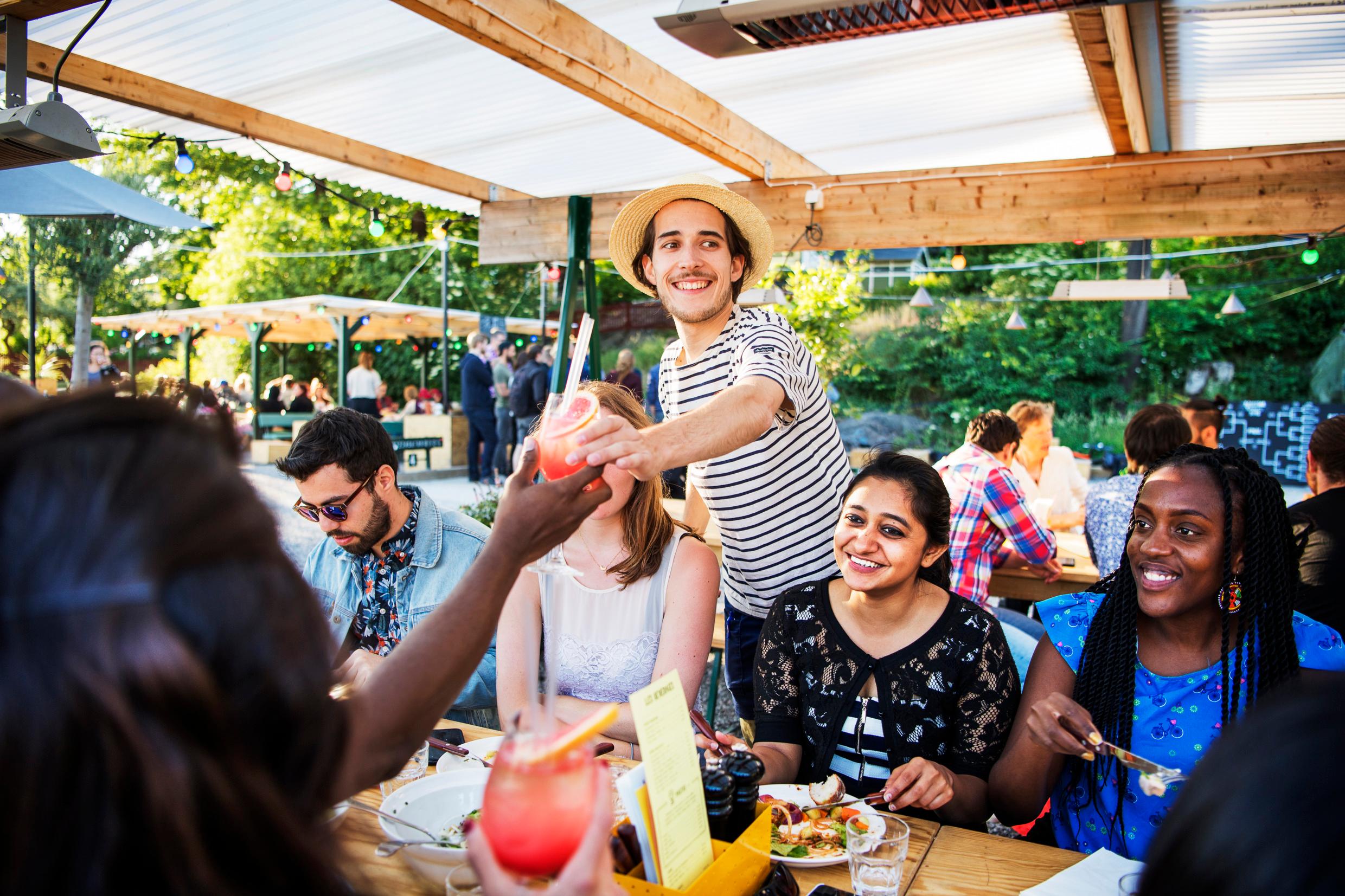 A crowded outdoor restaurant with people eating and drinking.