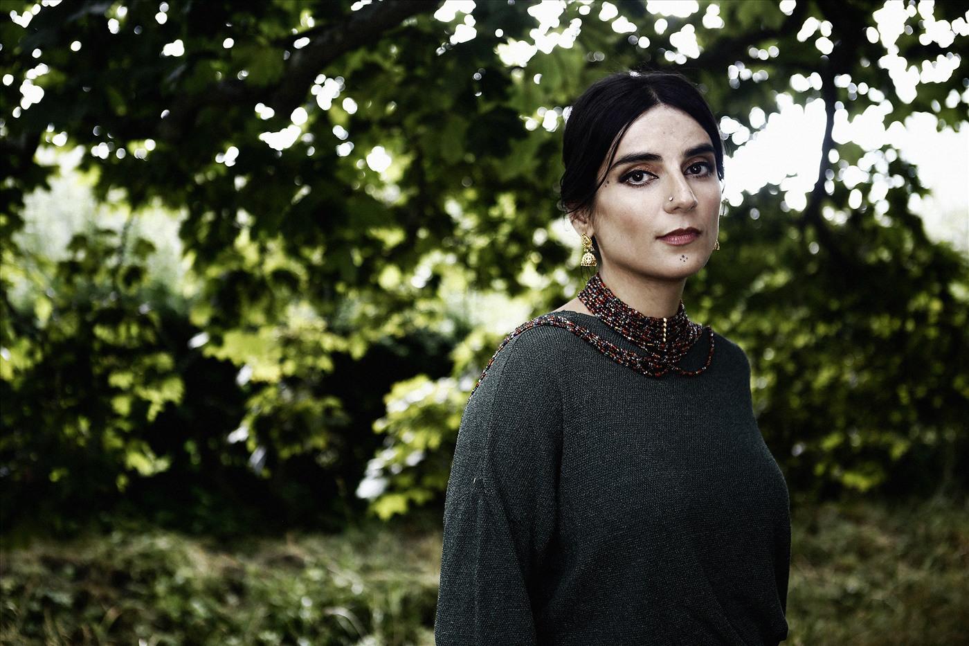 Portrait of a woman against a backdrop of green leaves.