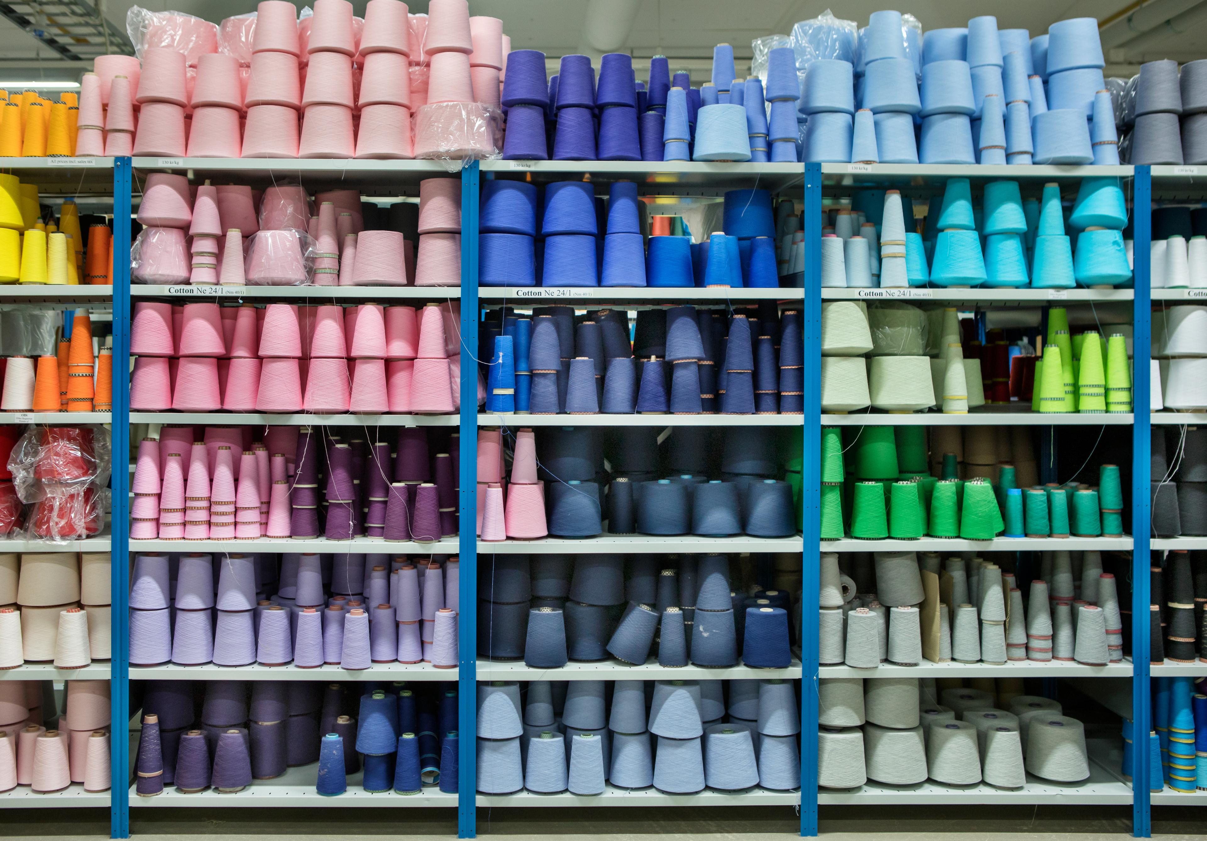 Shelves with a lot of large rolls of sewing thread in all the different color scales.