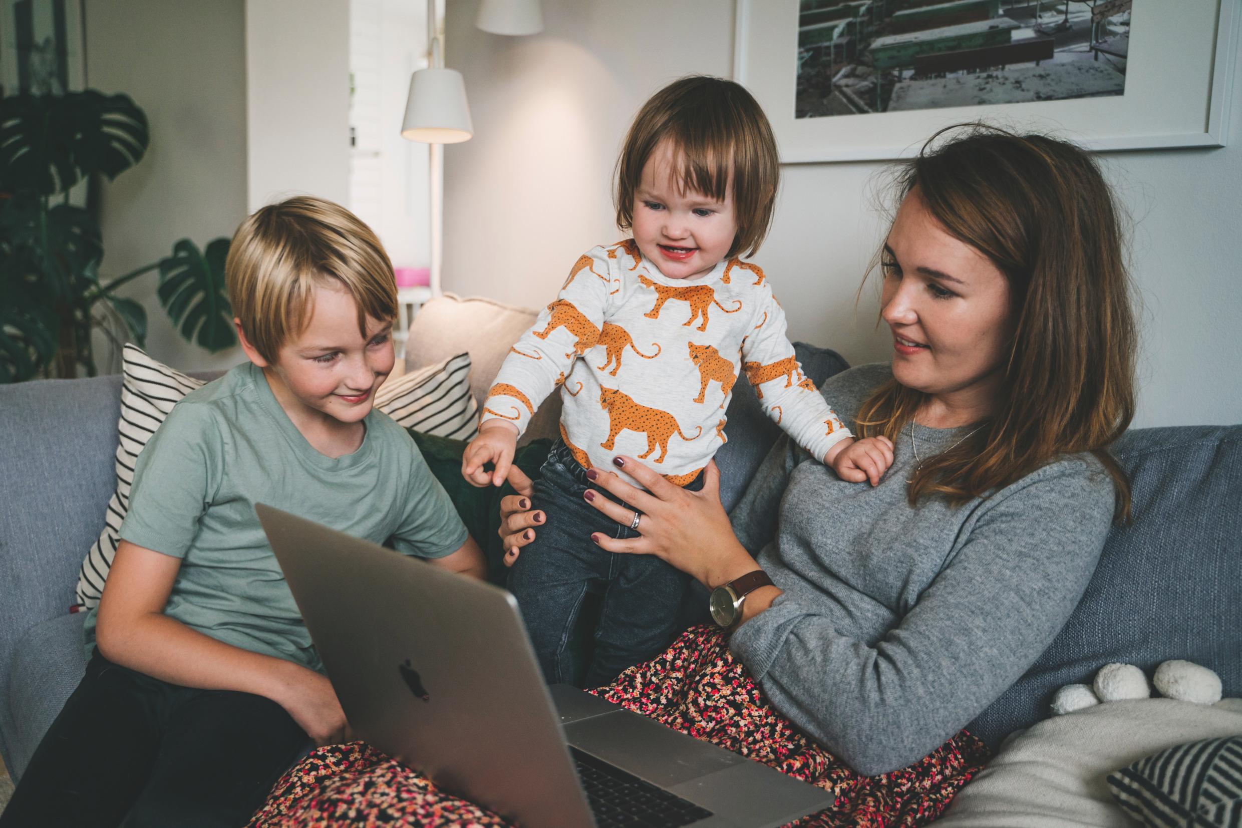 Family Family setting with a mother and children looking at a laptop screen.